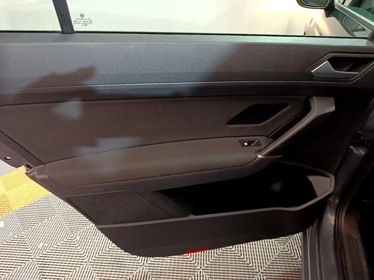 Intérieur côté gauche de la porte avant gris foncé du Volkswagen Touran 2023 avec poignée et commande de vitre.