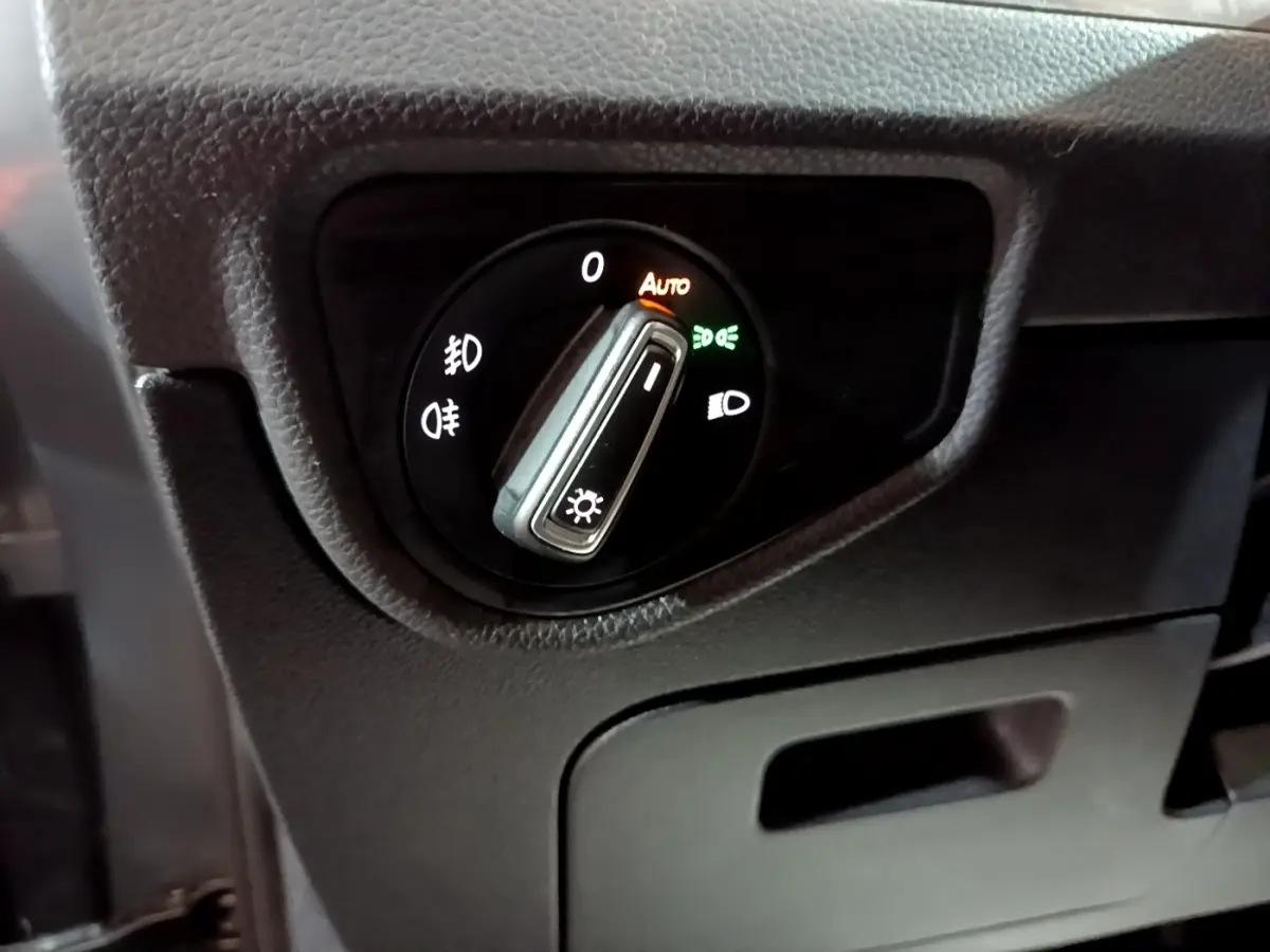 Gros plan sur le sélecteur de phares du tableau de bord du Volkswagen Touran gris foncé, mode automatique activé.