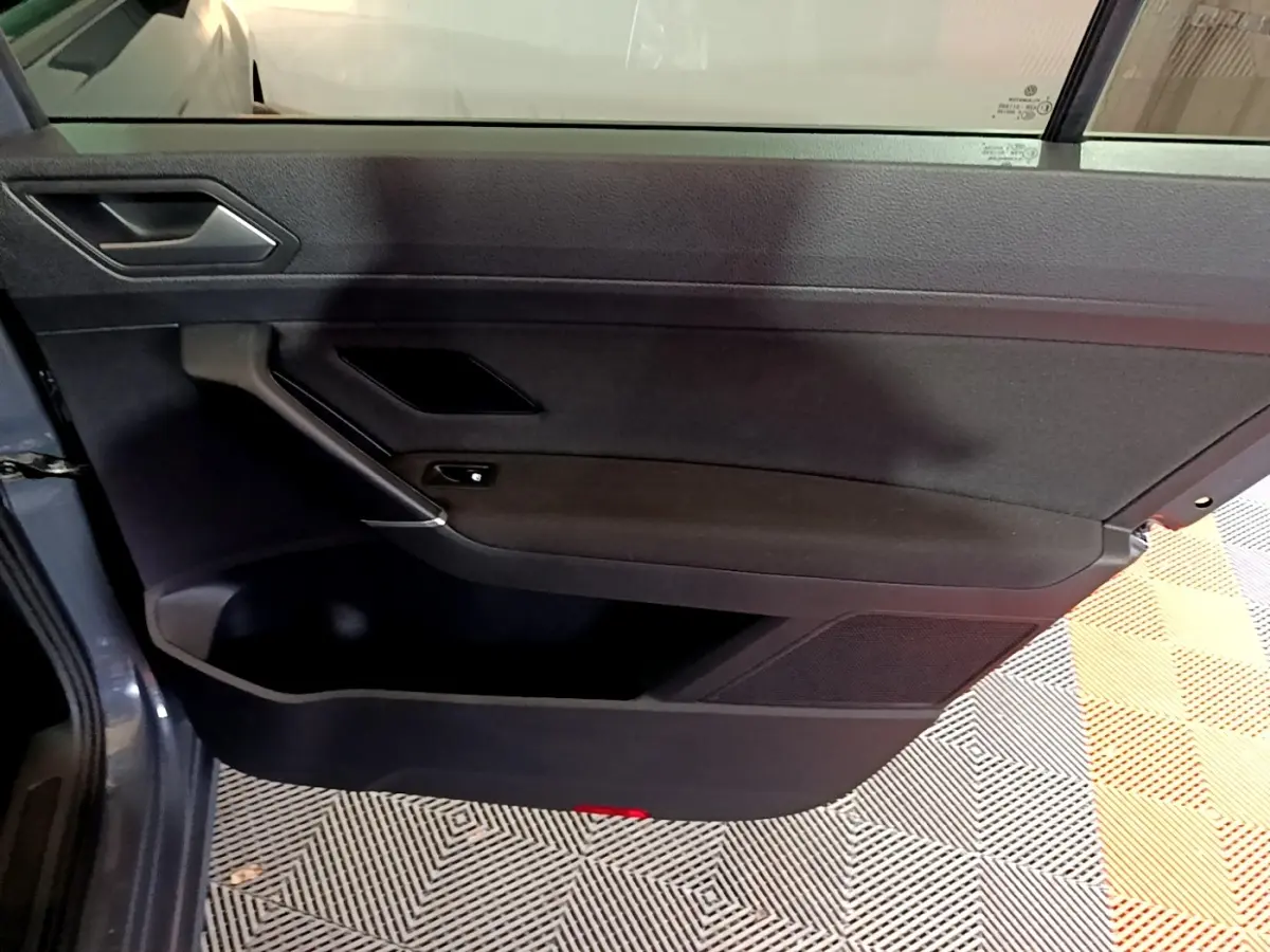 Porte arrière gauche ouverte du Volkswagen Touran gris foncé 2023, intérieur noir avec poignée et rangement visible.