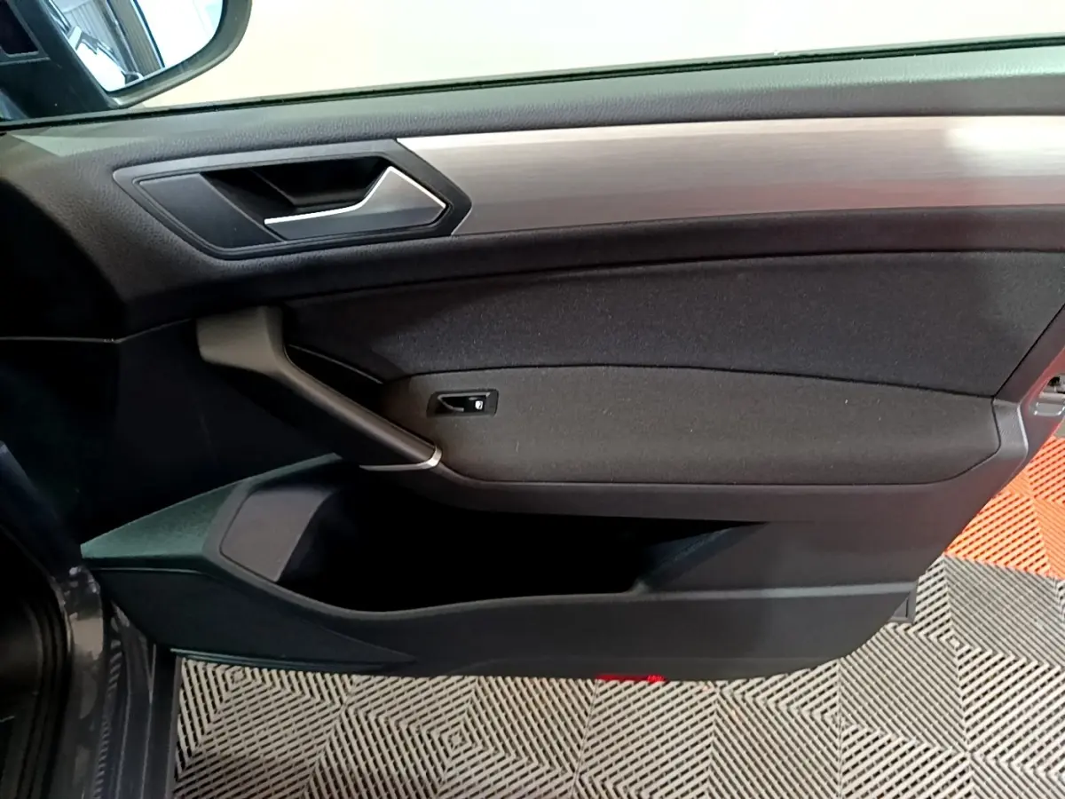 Porte intérieure côté gauche du Volkswagen Touran gris foncé 2023, avec poignée argentée et garniture noire.