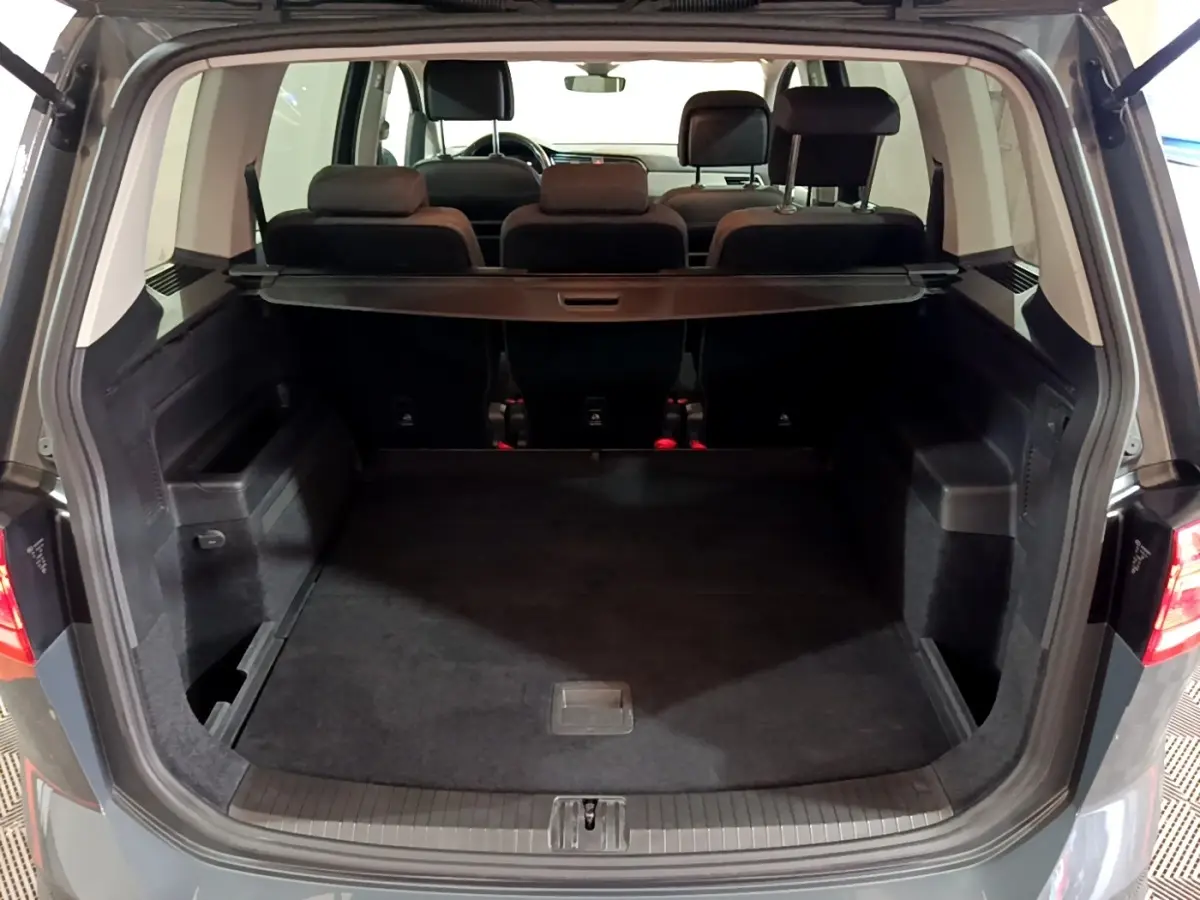 Vue arrière ouverte du coffre spacieux gris foncé du Volkswagen Touran 2.0 TDI 150 DSG7 Life Plus avec banquettes arrière visibles.
