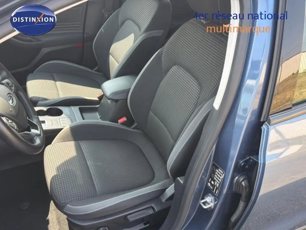 Vue intérieure côté conducteur de la Ford Focus SW bleu foncé, montrant les sièges avant et l'accoudoir central.