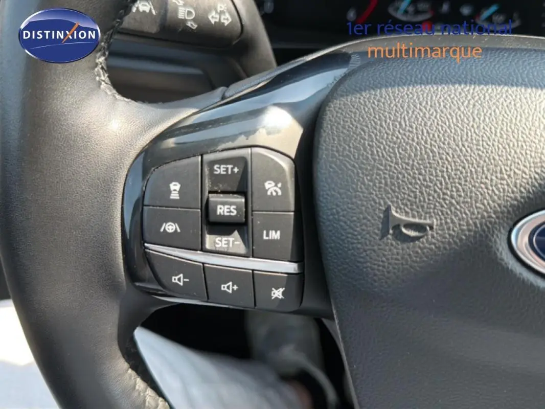 Gros plan sur le volant noir de la Ford Focus SW 2022, montrant les commandes du régulateur de vitesse et volume sonore.