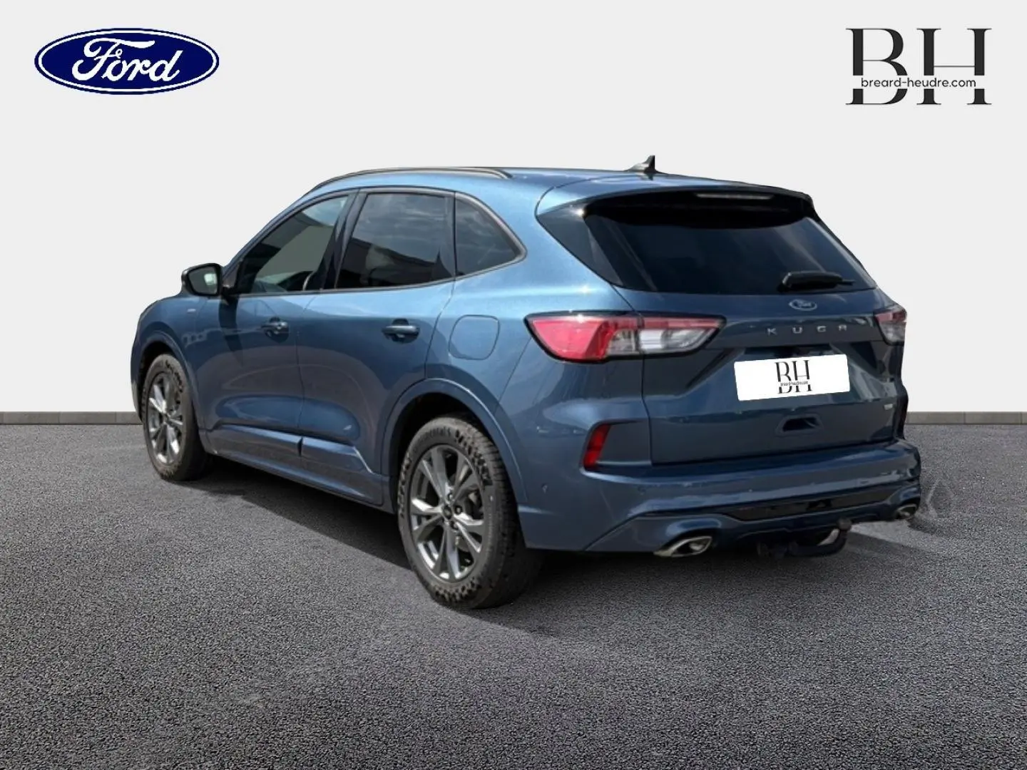 Ford Kuga bleu Abysse en 3/4 arrière droit, avec vitres surteintées et double sortie d’échappement visible.