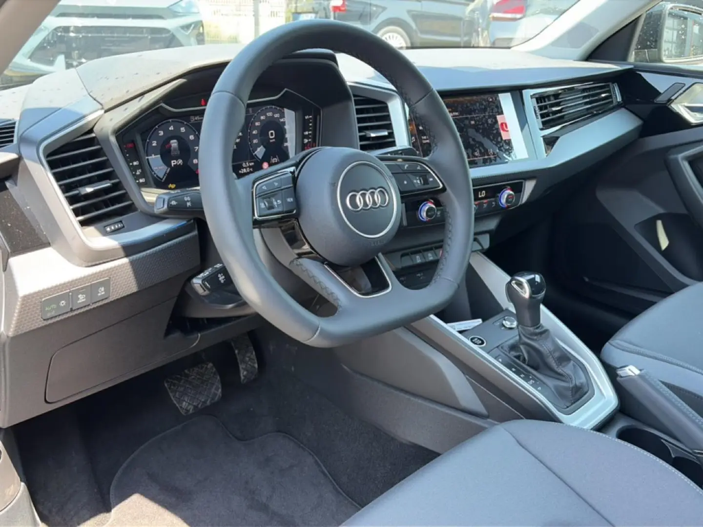Vue intérieure côté conducteur de l'Audi A1 Sportback 30 TFSI 2026, volant cuir et tableau de bord numérique.