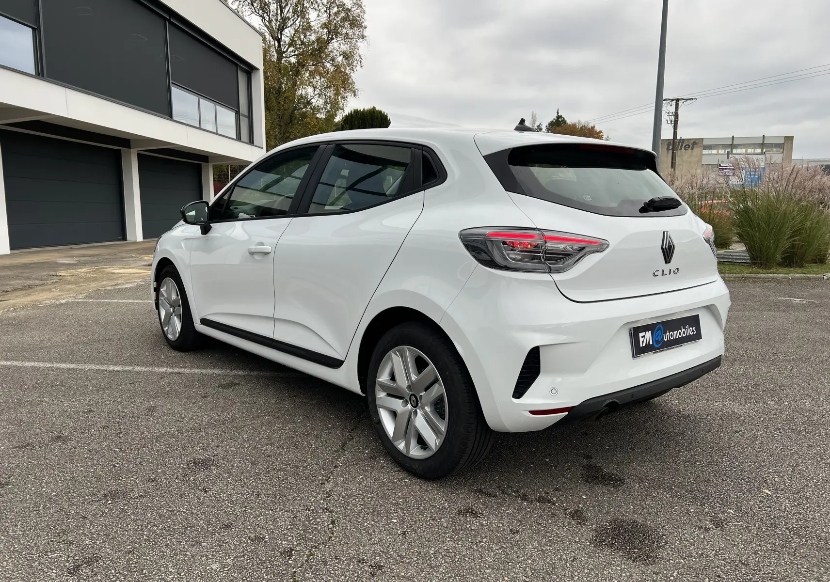 Vue 3/4 arrière droite d'une Renault Clio V blanche avec jantes 16 pouces et rétroviseurs noir perle.