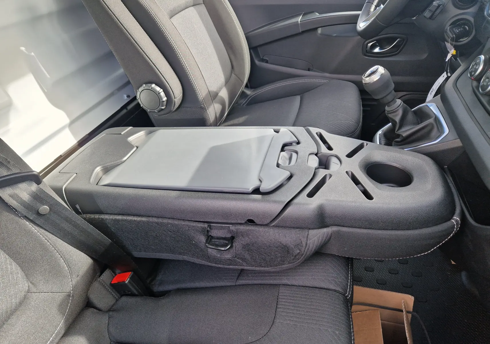 Vue intérieure côté droit du Nissan Primastar 2025, montrant les sièges gris urbain et la console centrale avec porte-gobelet.