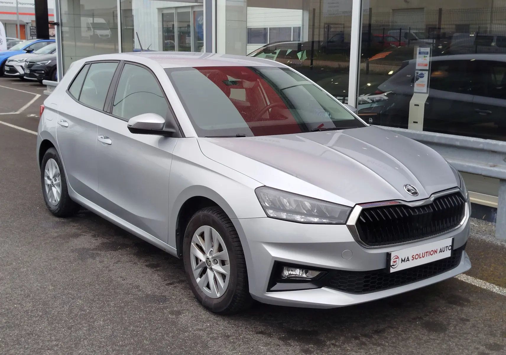 Vue 3/4 avant droite d'une Skoda Fabia 2023 gris argent métallisé avec calandre noire et phares LED.