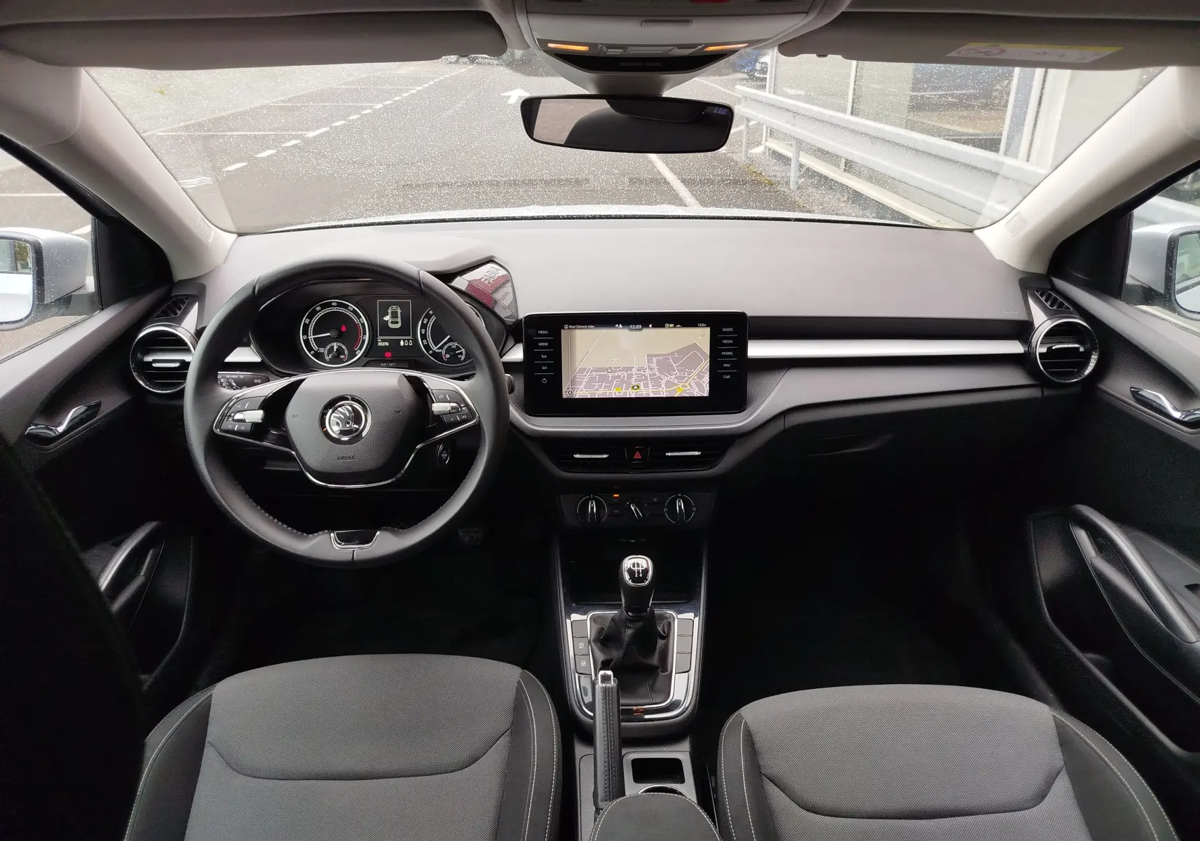 Vue intérieure frontale du poste de conduite de la Skoda Fabia gris argent, avec volant multifonction et écran tactile central.