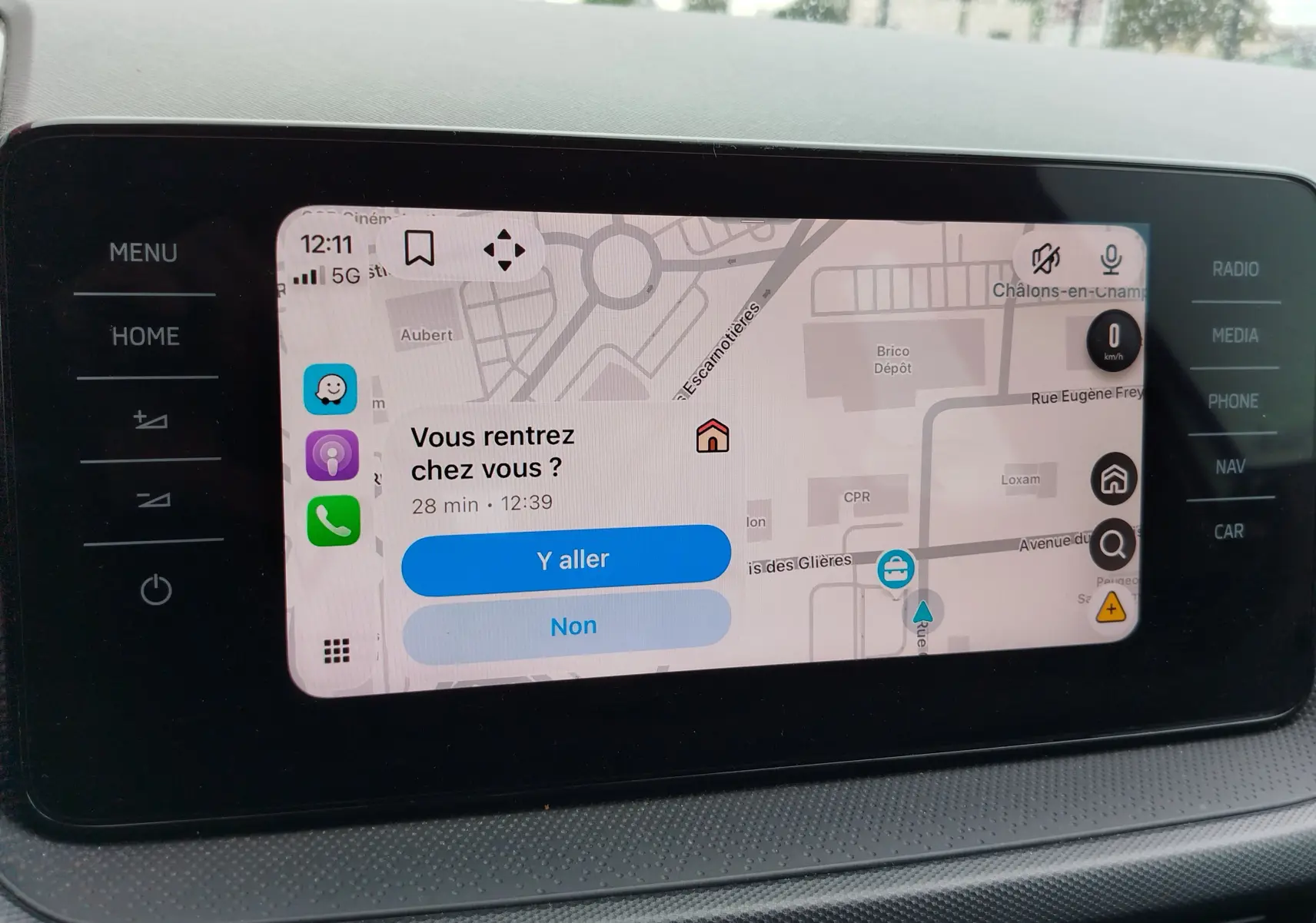 Écran central tactile de la Skoda Fabia 2023 affichant la navigation avec options vocales et boutons latéraux.