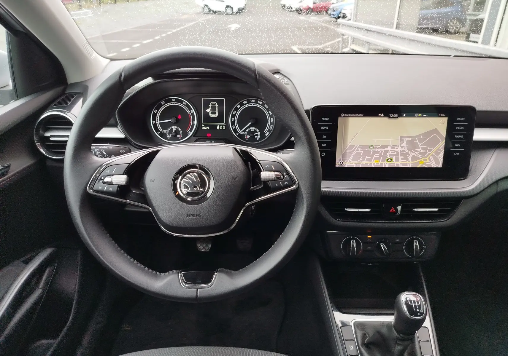 Vue intérieure frontale du poste de conduite de la Skoda Fabia 2023 avec volant multifonction et écran tactile de navigation.