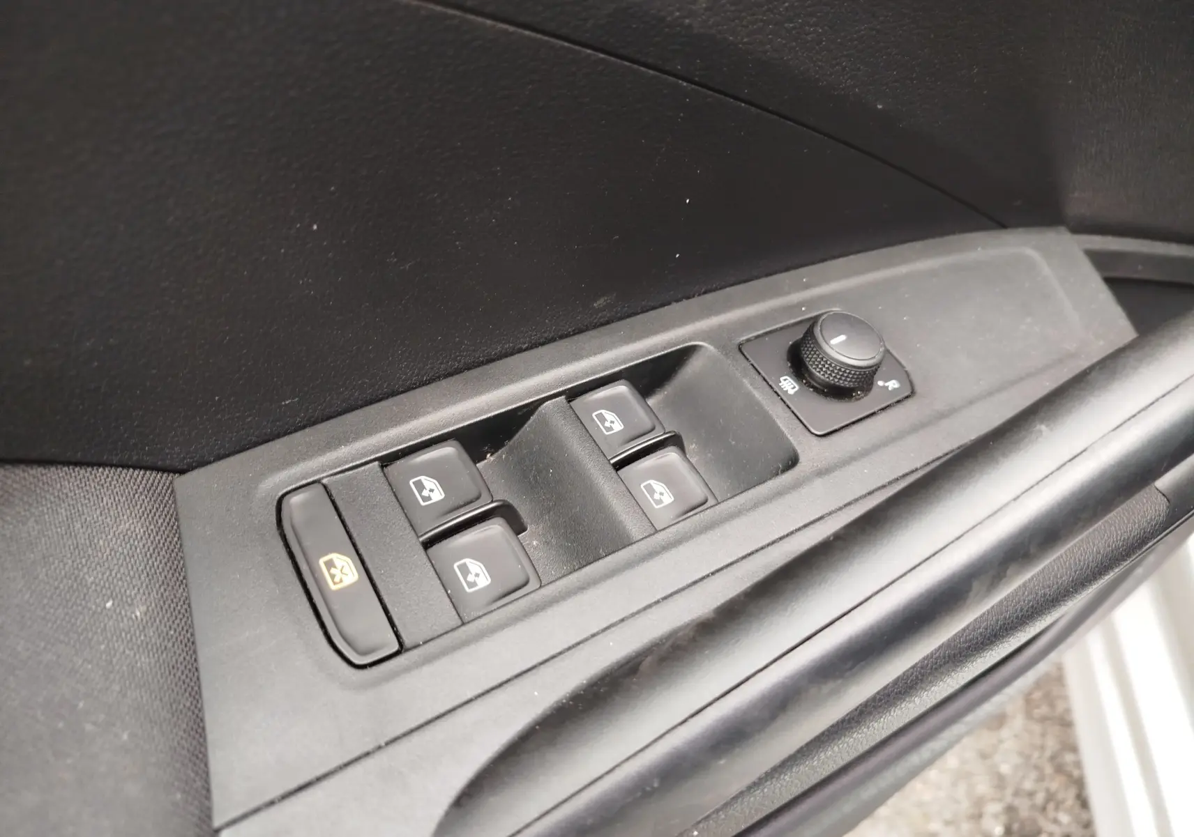 Gros plan sur les commandes de lève-vitres et réglage des rétroviseurs côté conducteur d'une Skoda Fabia gris argent 2023.
