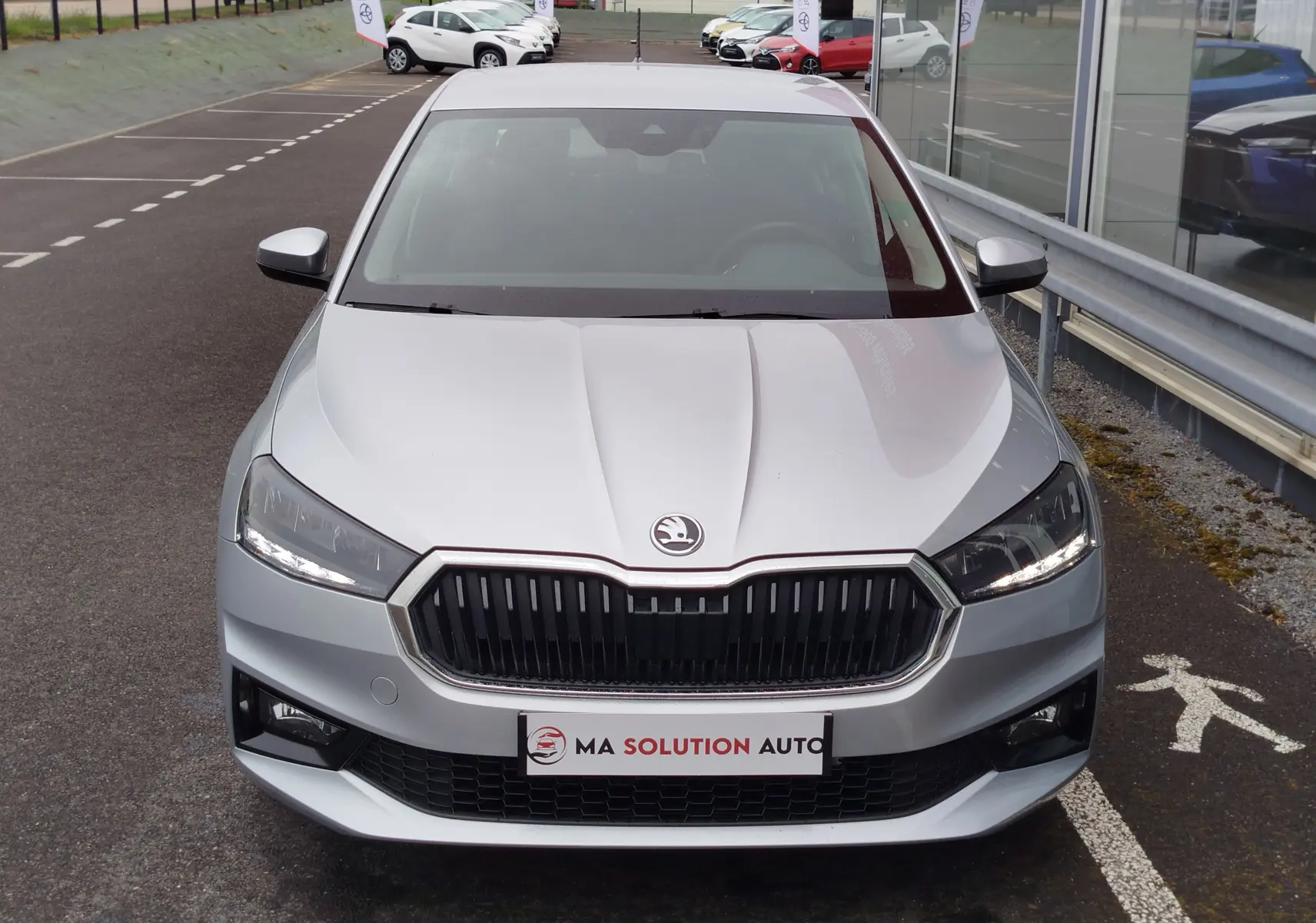 Vue avant d'une Skoda Fabia 2023 gris argent métallisé, avec calandre noire et phares LED allumés.