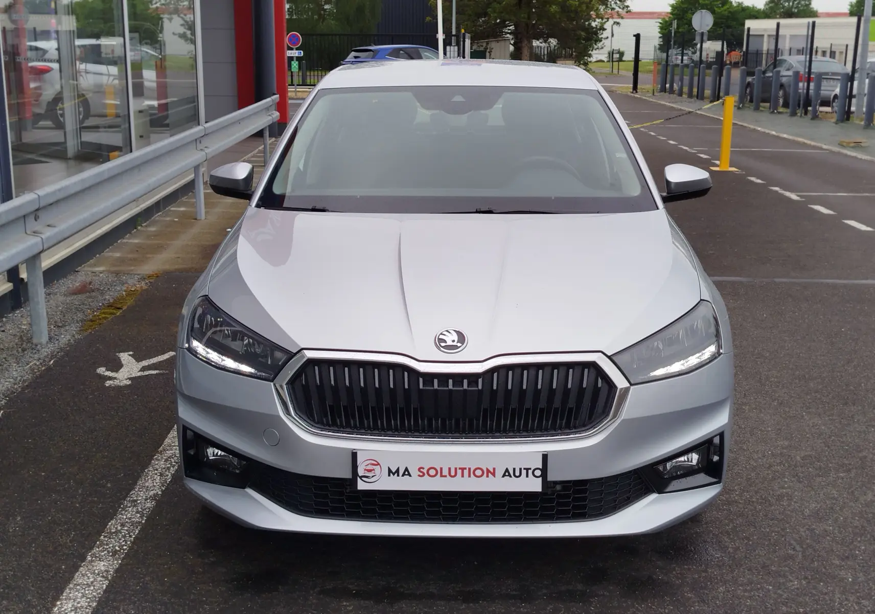 Vue avant frontale d'une Skoda Fabia gris argent métallisé avec calandre noire et phares LED allumés.