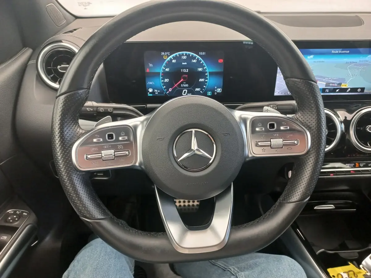 Vue intérieure centrée sur le volant cuir perforé de la Mercedes Classe A A 200 AMG Line avec tableau de bord numérique et écran tactile.