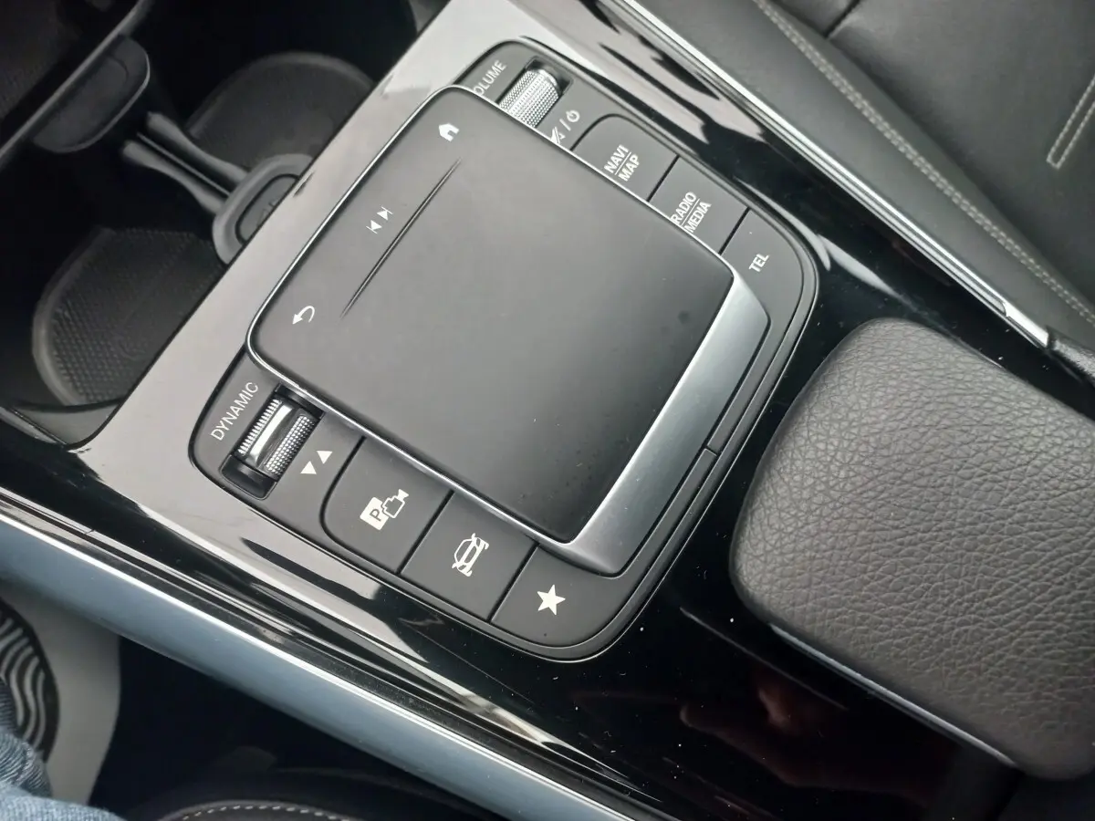 Vue rapprochée de la console centrale noire brillante avec pavé tactile et commandes du Mercedes Classe A Berline A 200 AMG Line.