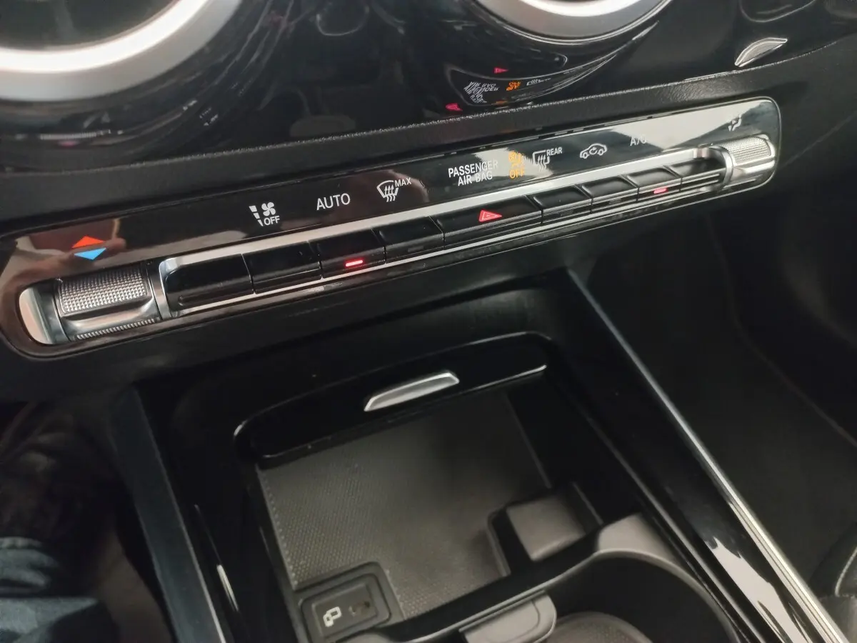 Gros plan sur la console centrale noire de la Mercedes Classe A A 200 AMG Line, avec commandes climatisation et rangement.