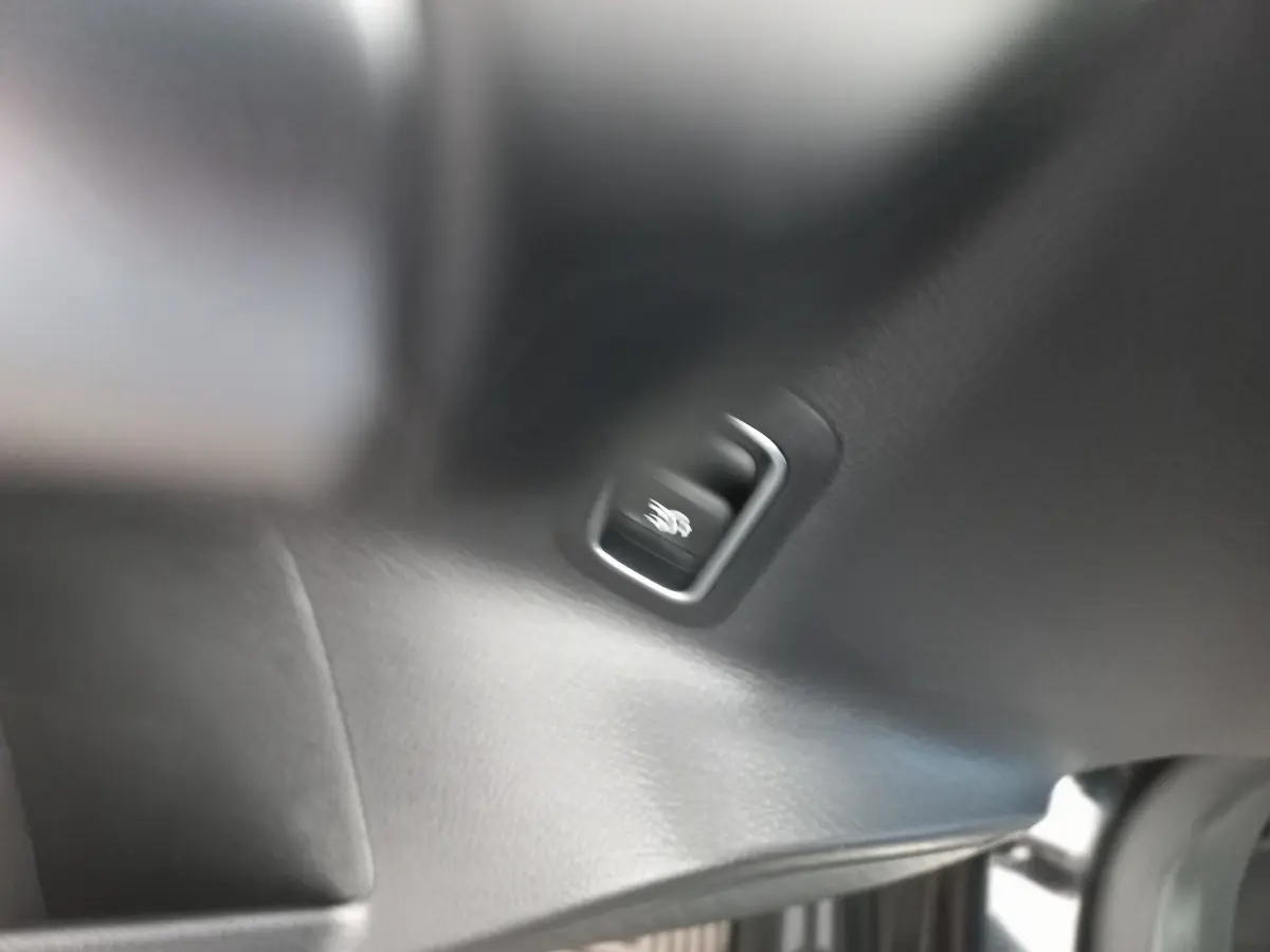 Détail du bouton de libération du coffre sur la garniture intérieure noire d’une Mercedes Classe A Berline A 200 AMG Line.