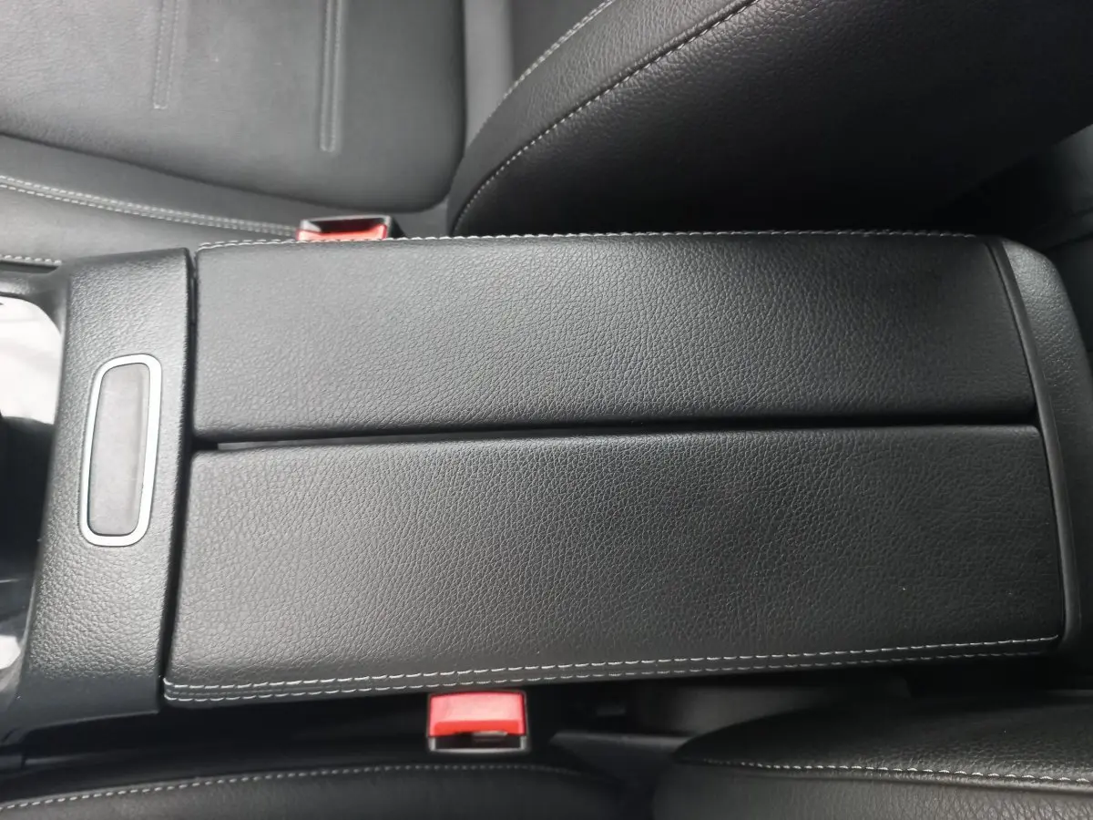 Vue rapprochée de l'accoudoir central en cuir noir avec surpiqûres blanches dans une Mercedes Classe A Berline A 200 AMG Line.