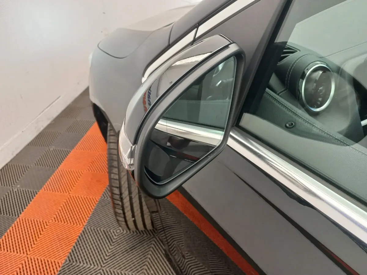 Gros plan sur le rétroviseur droit noir brillant d’une Mercedes Classe A Berline A 200 AMG Line 2021, intérieur cuir visible.