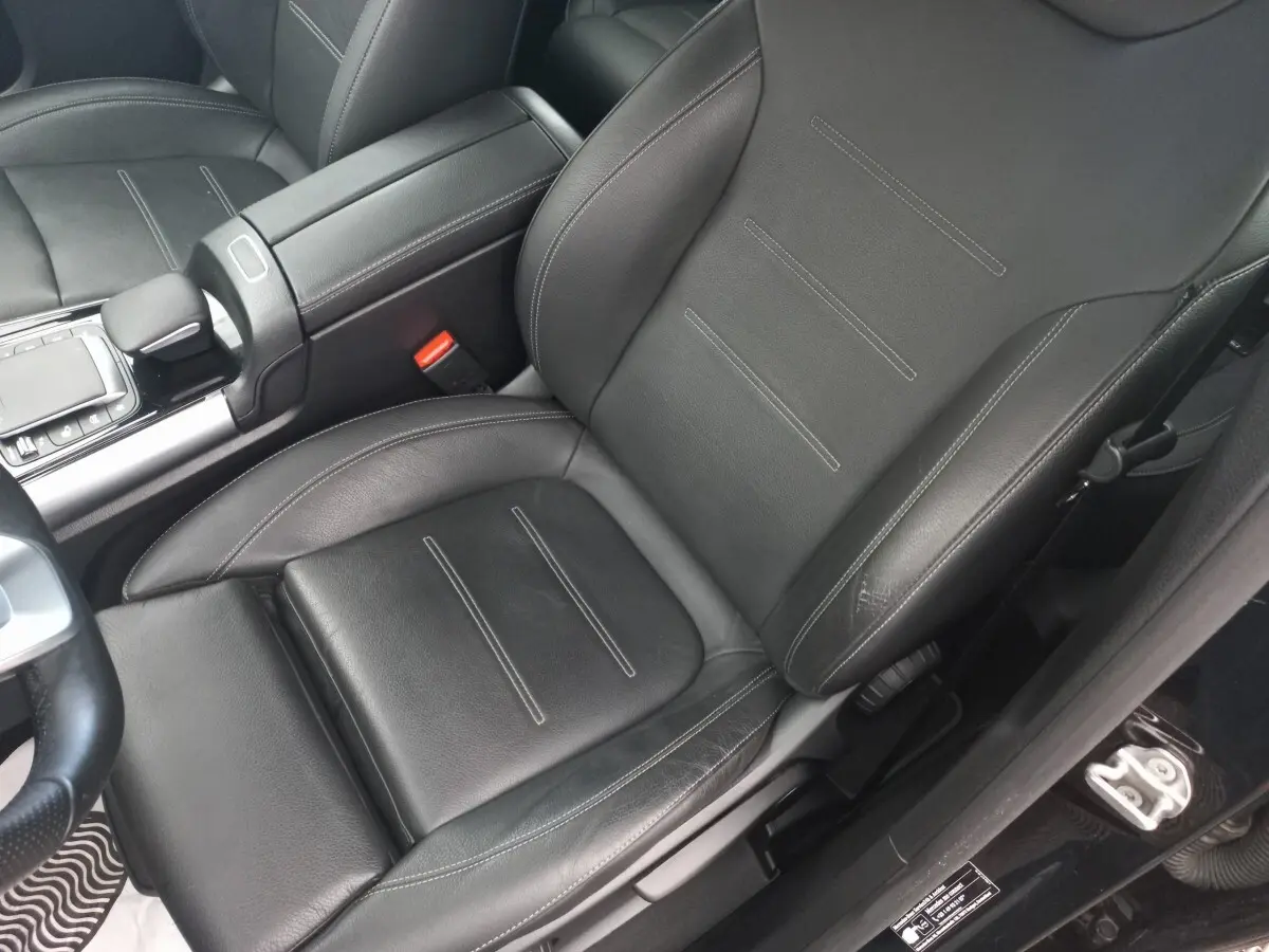 Gros plan sur le siège avant gauche en cuir noir avec surpiqûres blanches de la Mercedes Classe A Berline A 200 AMG Line 2021.