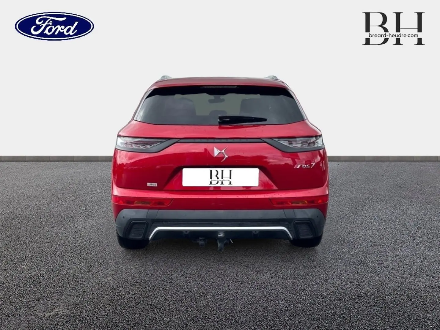 Vue arrière d'un DS7 Crossback rouge Absolu avec feux arrière LED et attelage visible sur sol goudronné.