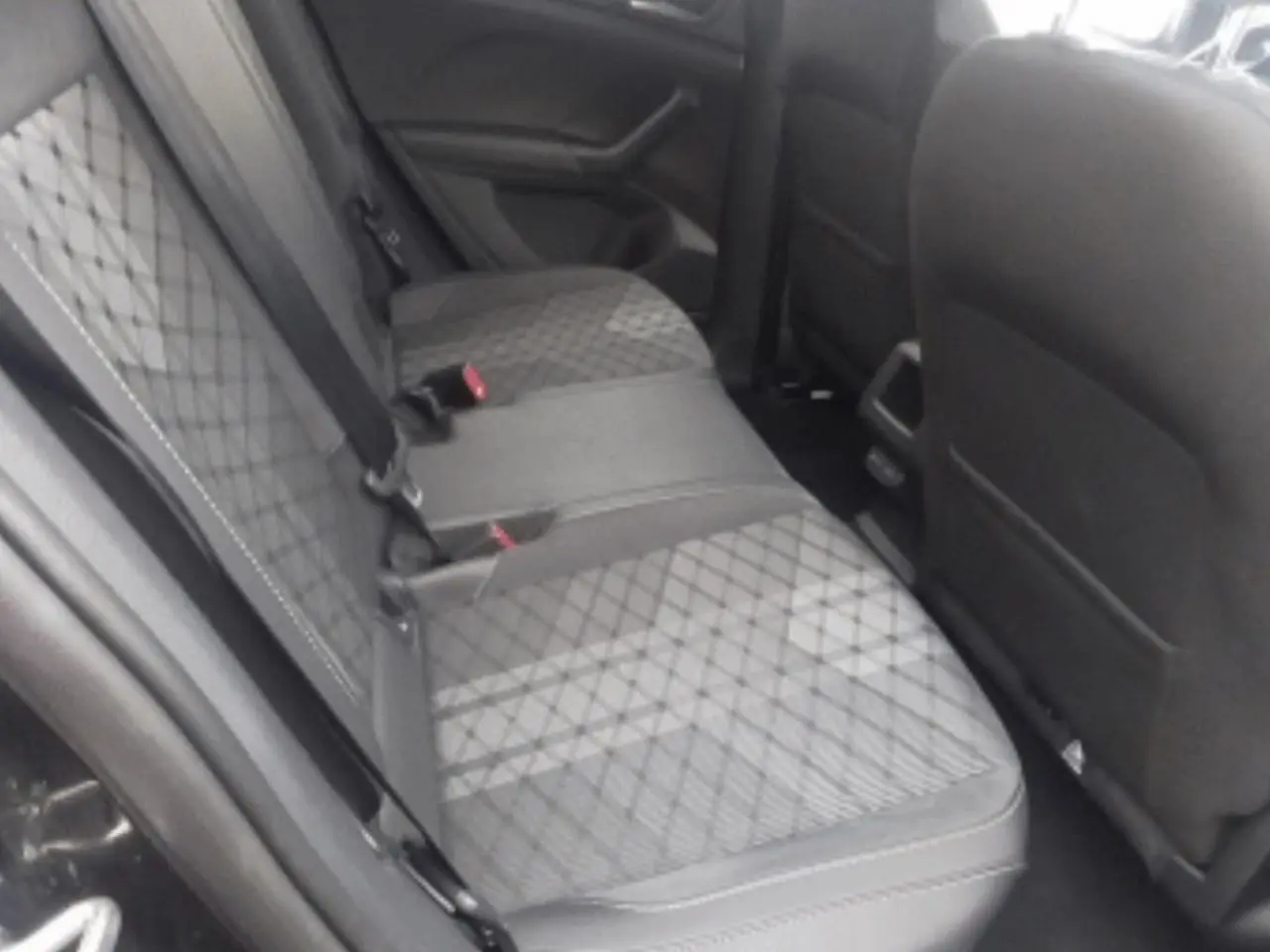 Vue intérieure du siège arrière côté gauche d’un Volkswagen T-Cross 2025 noir métal avec sellerie tissu à motifs losanges.