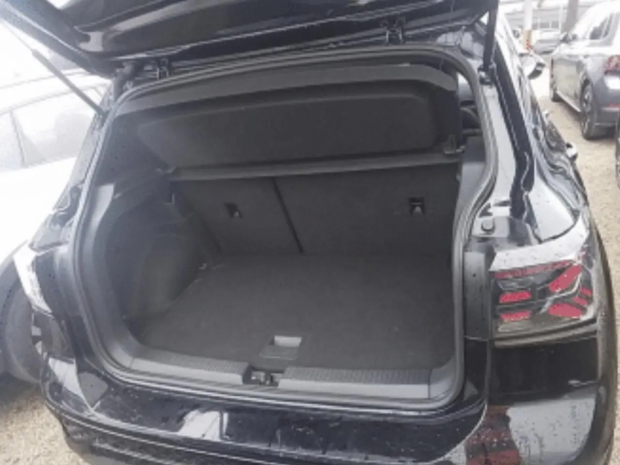 Vue arrière du Volkswagen T-Cross noir métal 2025 avec coffre ouvert, mettant en valeur ses feux arrière distinctifs.