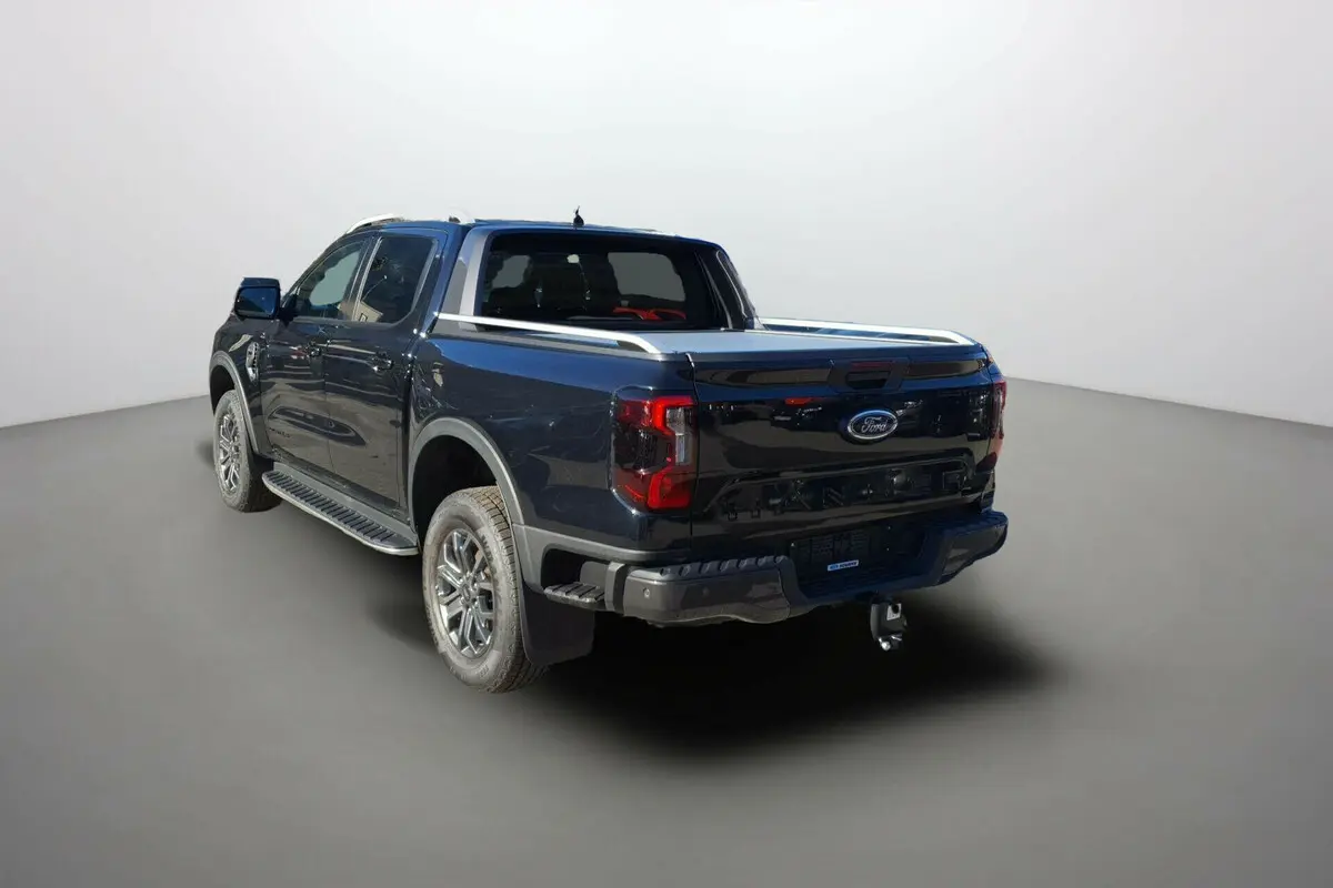 Ford Ranger 3.0 V6 240 Wildtrak Plus noir agate vu en 3/4 arrière droit avec attelage et barres de caisse chromées.