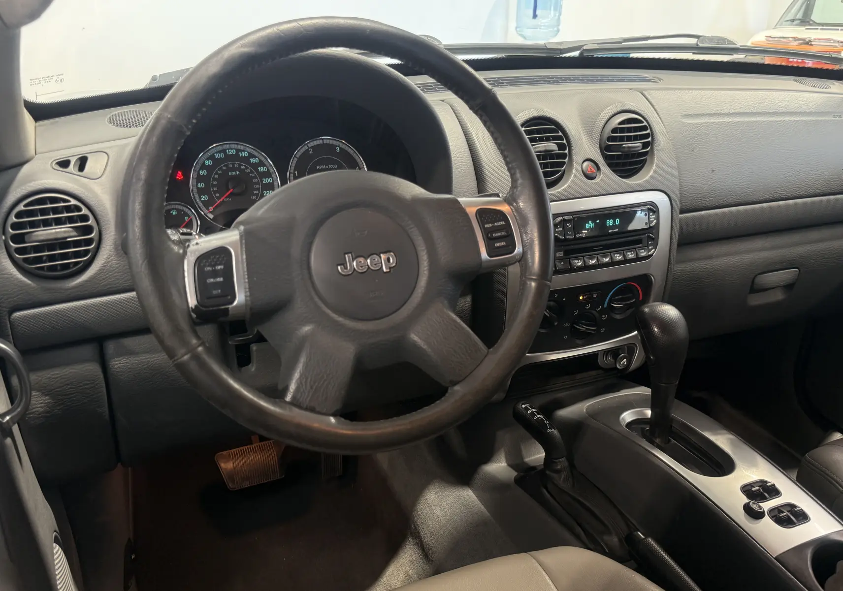 Intérieur du Jeep Cherokee 2005 bleu, vue du tableau de bord avec volant, console centrale et levier de vitesses automatique.