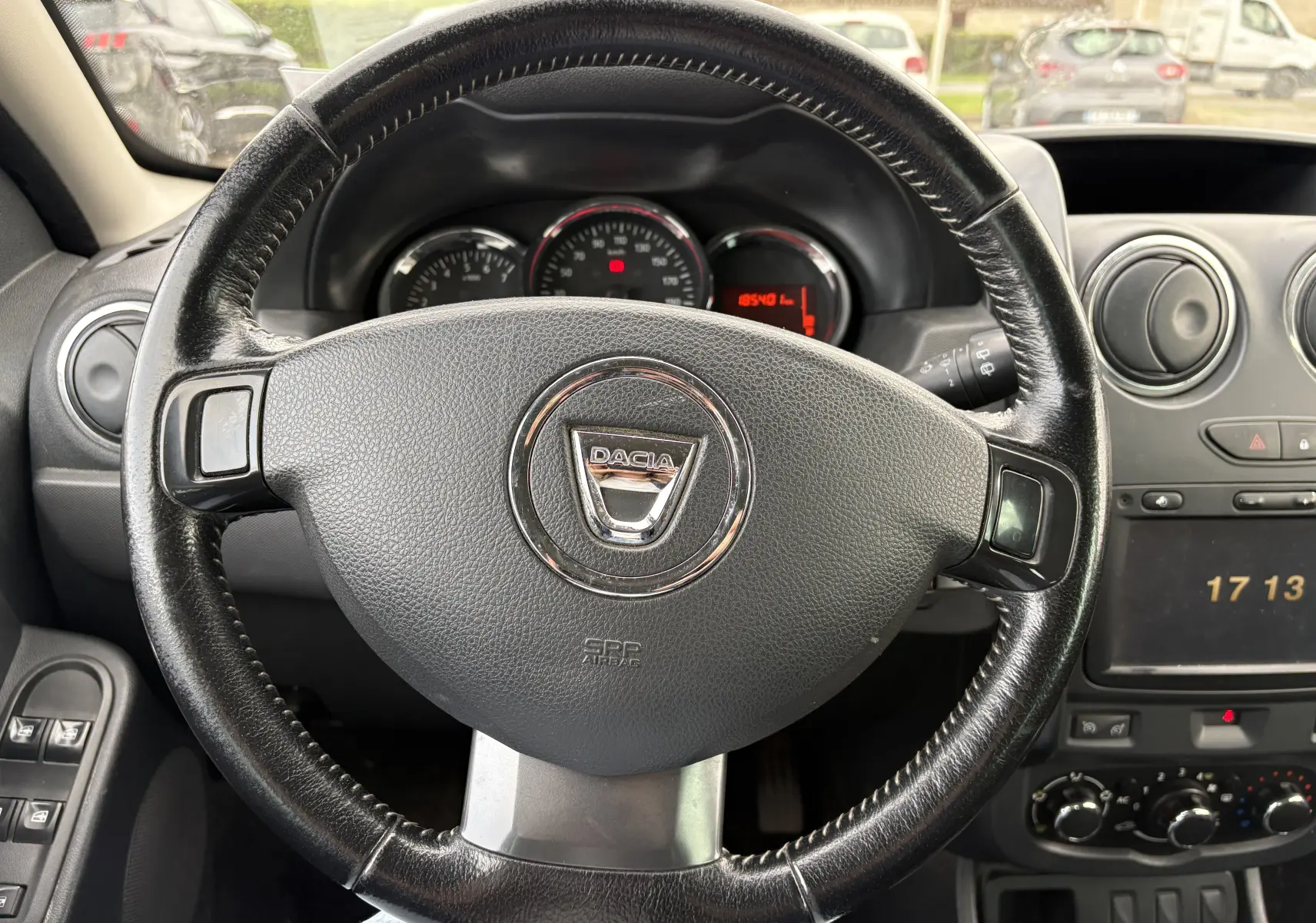 Vue intérieure centrée sur le volant noir du Dacia Duster 1.5 DCI 110 de 2014 avec tableau de bord et commandes visibles.