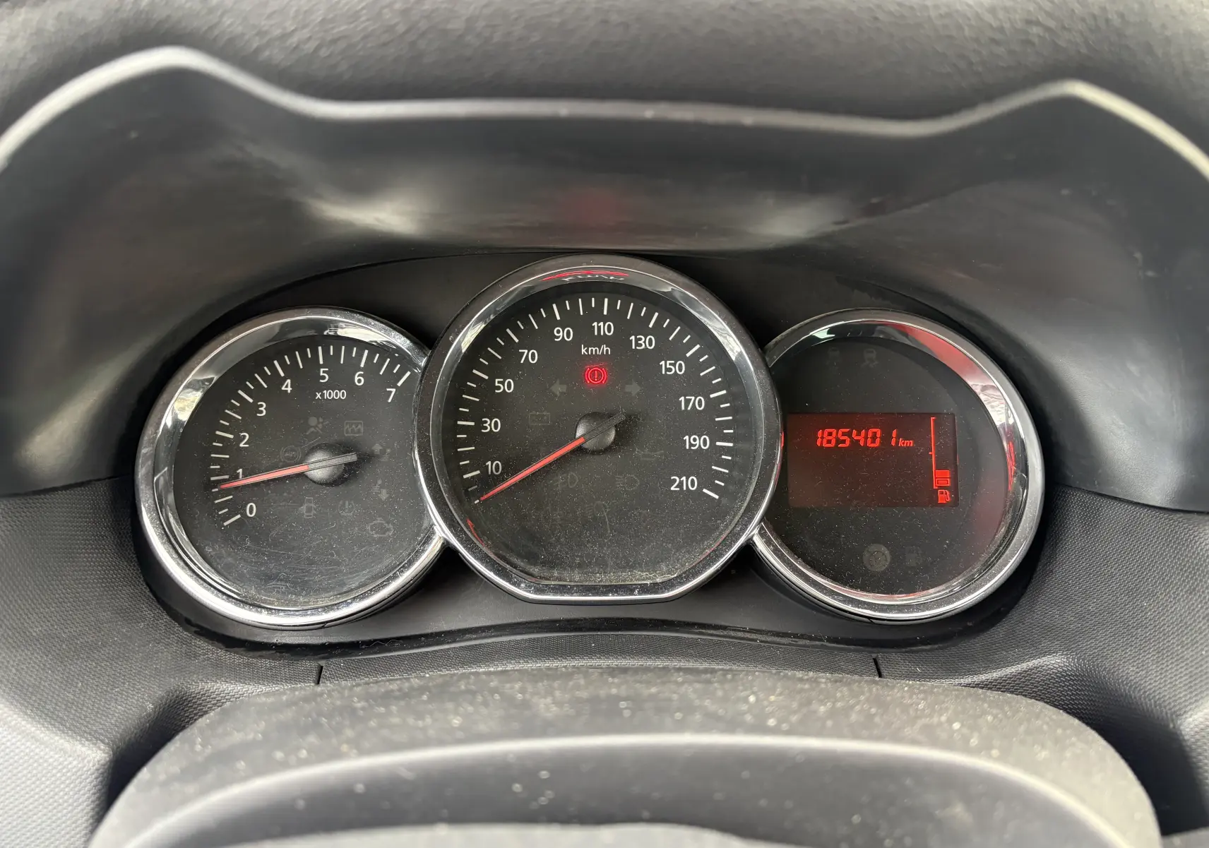 Gros plan sur le tableau de bord du Dacia Duster 2014, avec compte-tours, compteur de vitesse et affichage digital rouge.