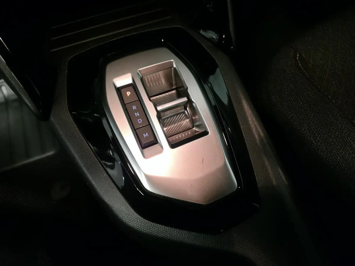 Gros plan sur la commande de boîte automatique argentée du Peugeot 2008 gris, avec levier et boutons P, R, N, D, M.