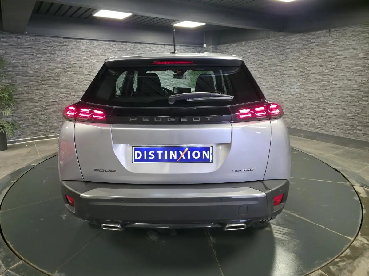 Vue arrière d'un Peugeot 2008 gris métallisé avec feux arrière LED allumés et double sortie d'échappement chromée.