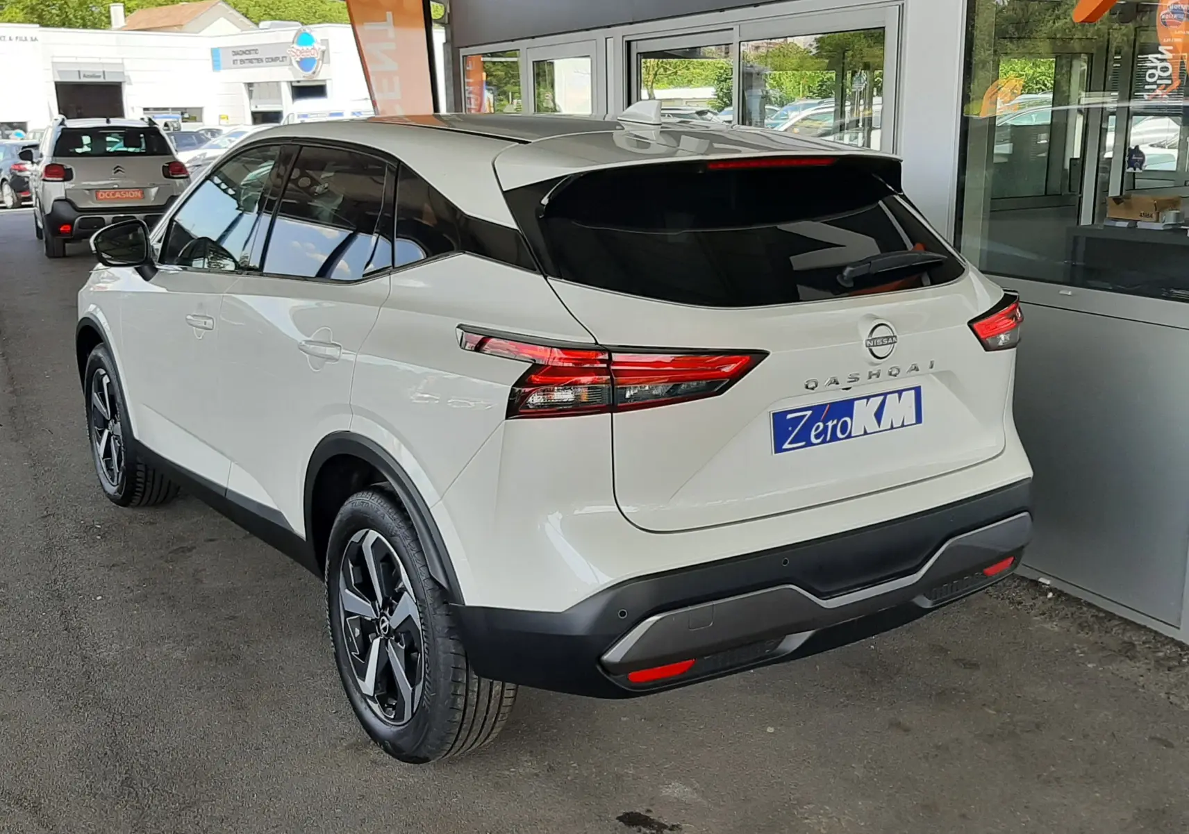 Vue 3/4 arrière droite d'un Nissan Qashqai blanc lunaire 2022 avec feux arrière LED et toit noir contrasté.