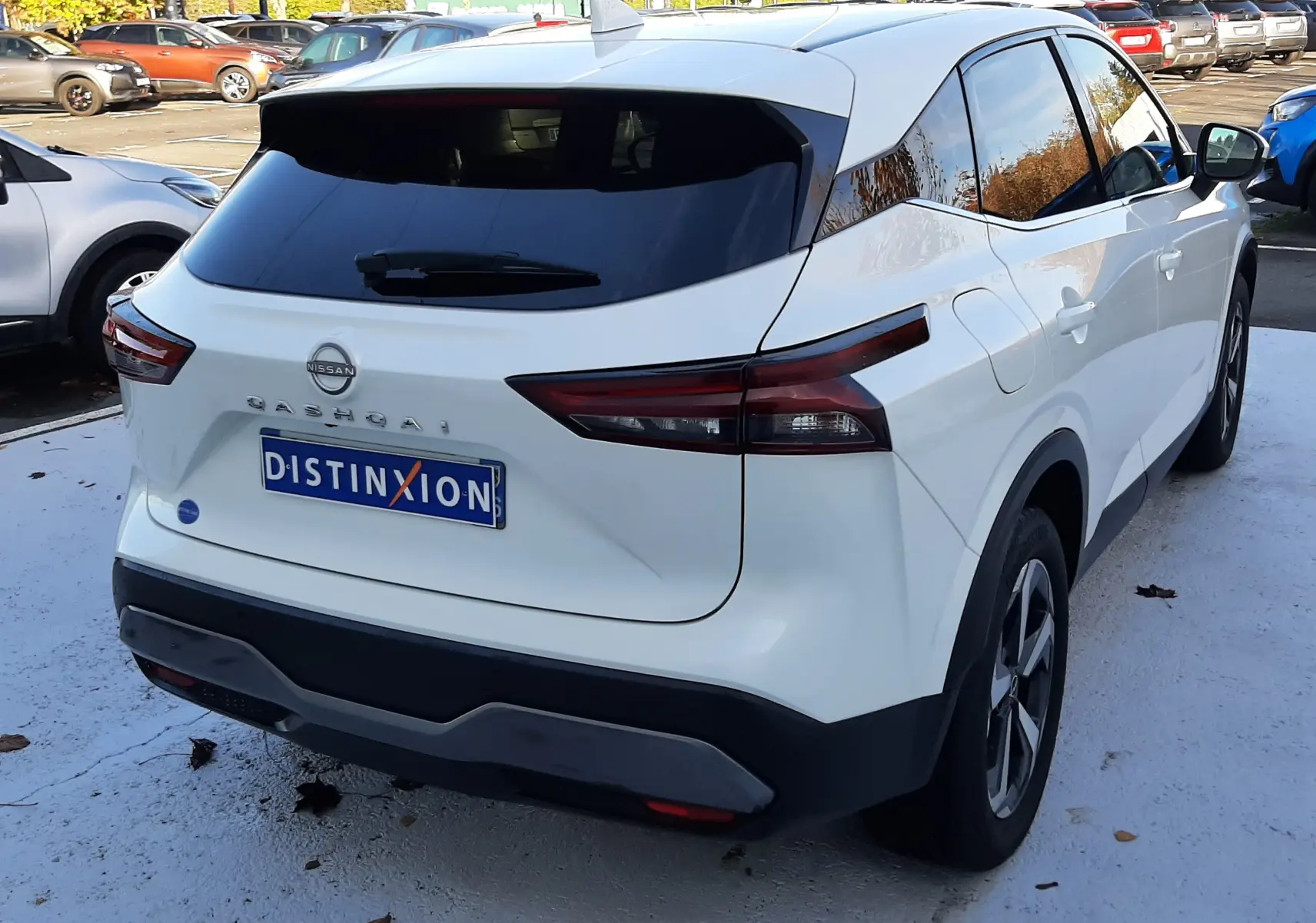 Vue 3/4 arrière droite d'un Nissan Qashqai blanc lunaire 2022 avec vitres teintées et feux arrière LED distinctifs.