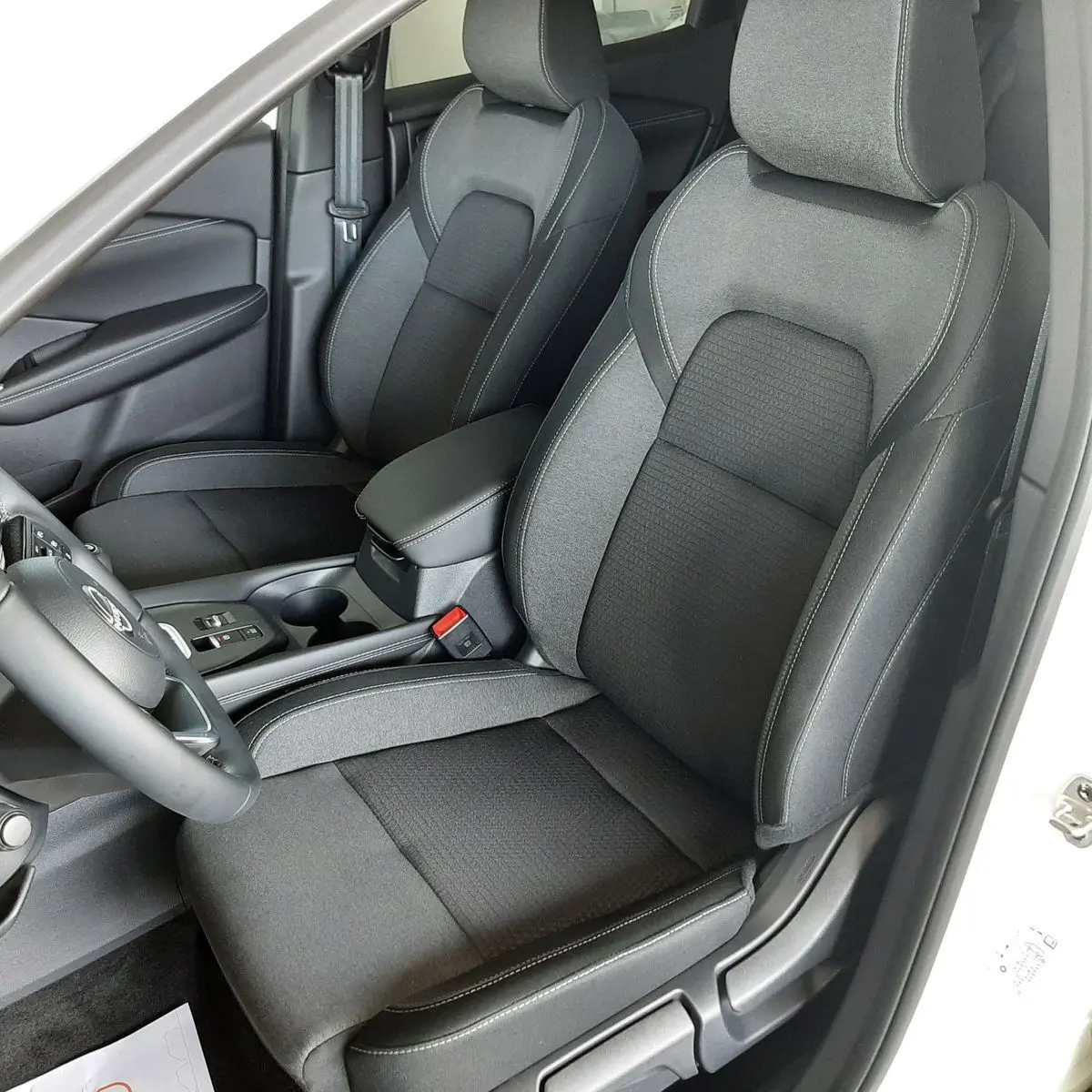 Vue intérieure côté conducteur du Nissan Qashqai blanc lunaire 2022, sièges tissu gris foncé avec surpiqûres claires.