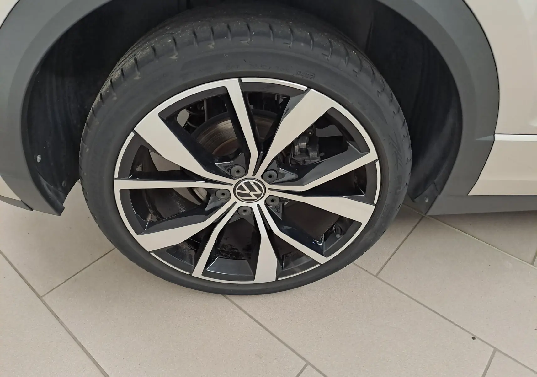 Gros plan sur la jante 19'' Misano bicolore noir et argent du côté gauche du Volkswagen T-Roc Cabriolet gris ivoire.