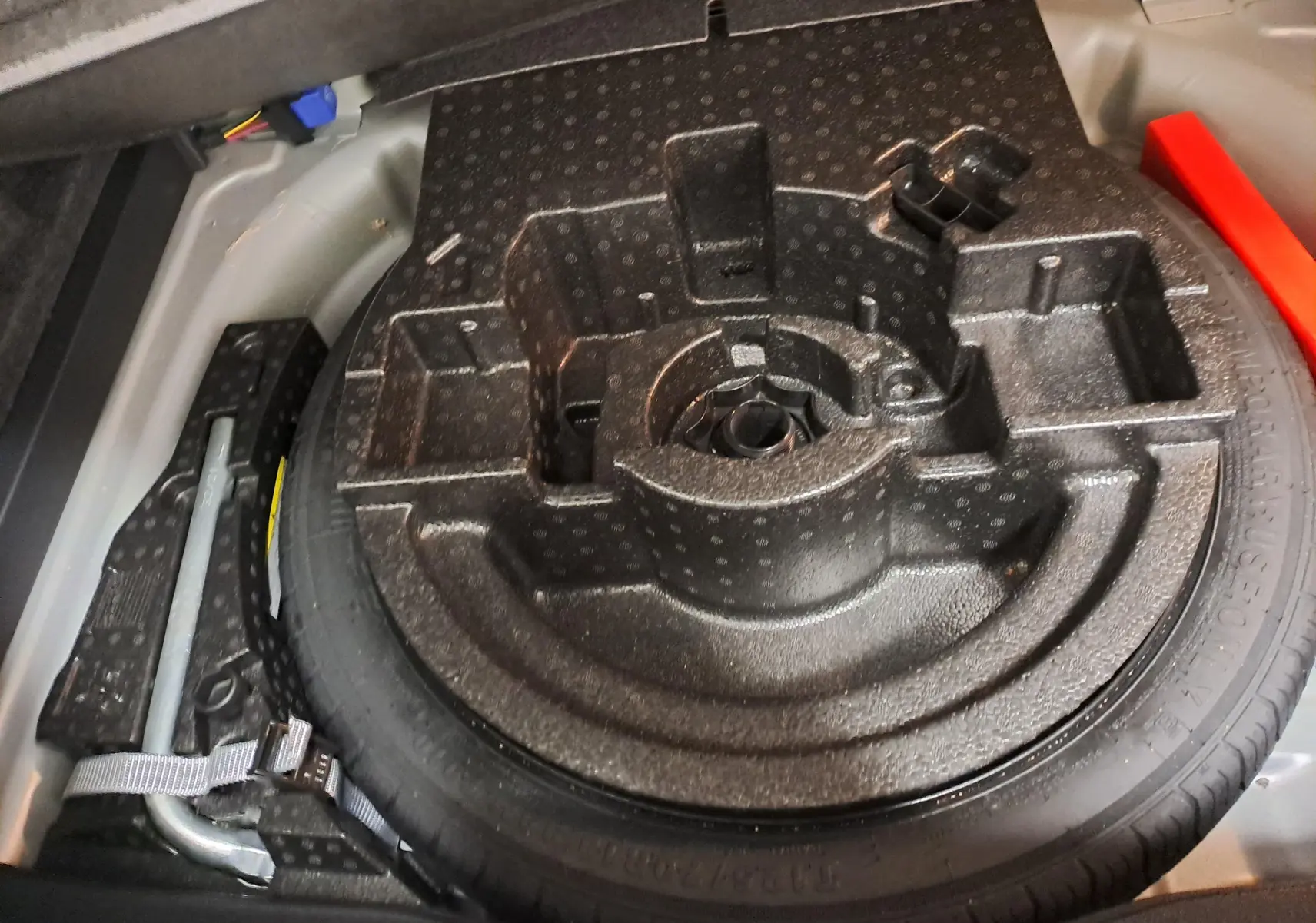 Gros plan sur la roue de secours compacte et le cric dans le coffre du Volkswagen T-Roc Cabriolet 2022.