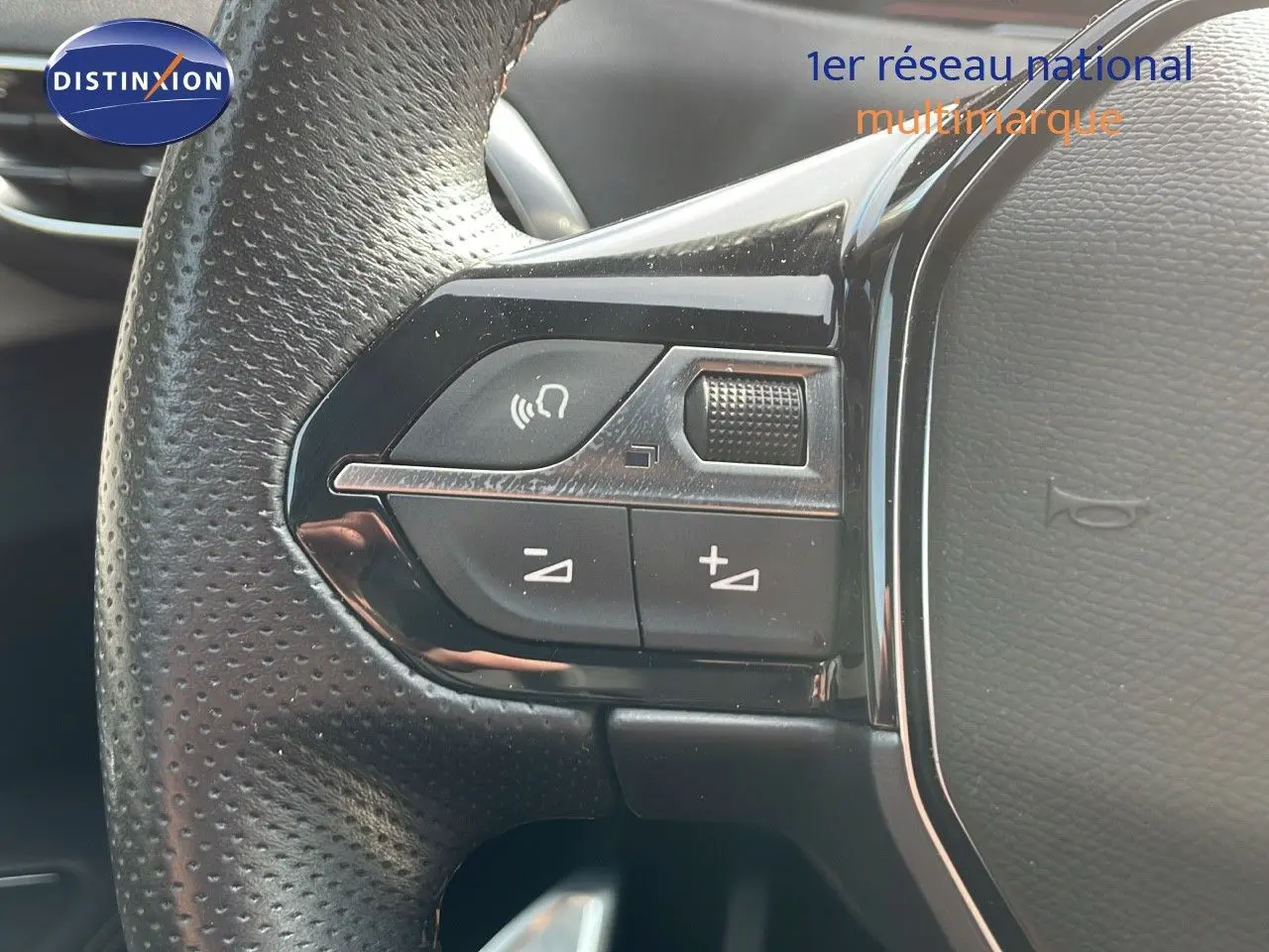 Gros plan sur les commandes au volant en cuir perforé noir du Peugeot 3008 gris platinium 2023.