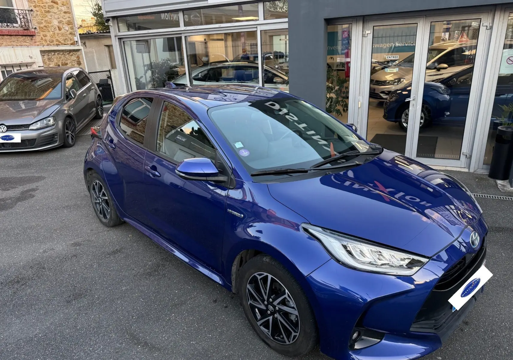 Toyota Yaris Hybride Design 116h bleu métal vue 3/4 avant droit avec jantes alliage et phares LED allumés.