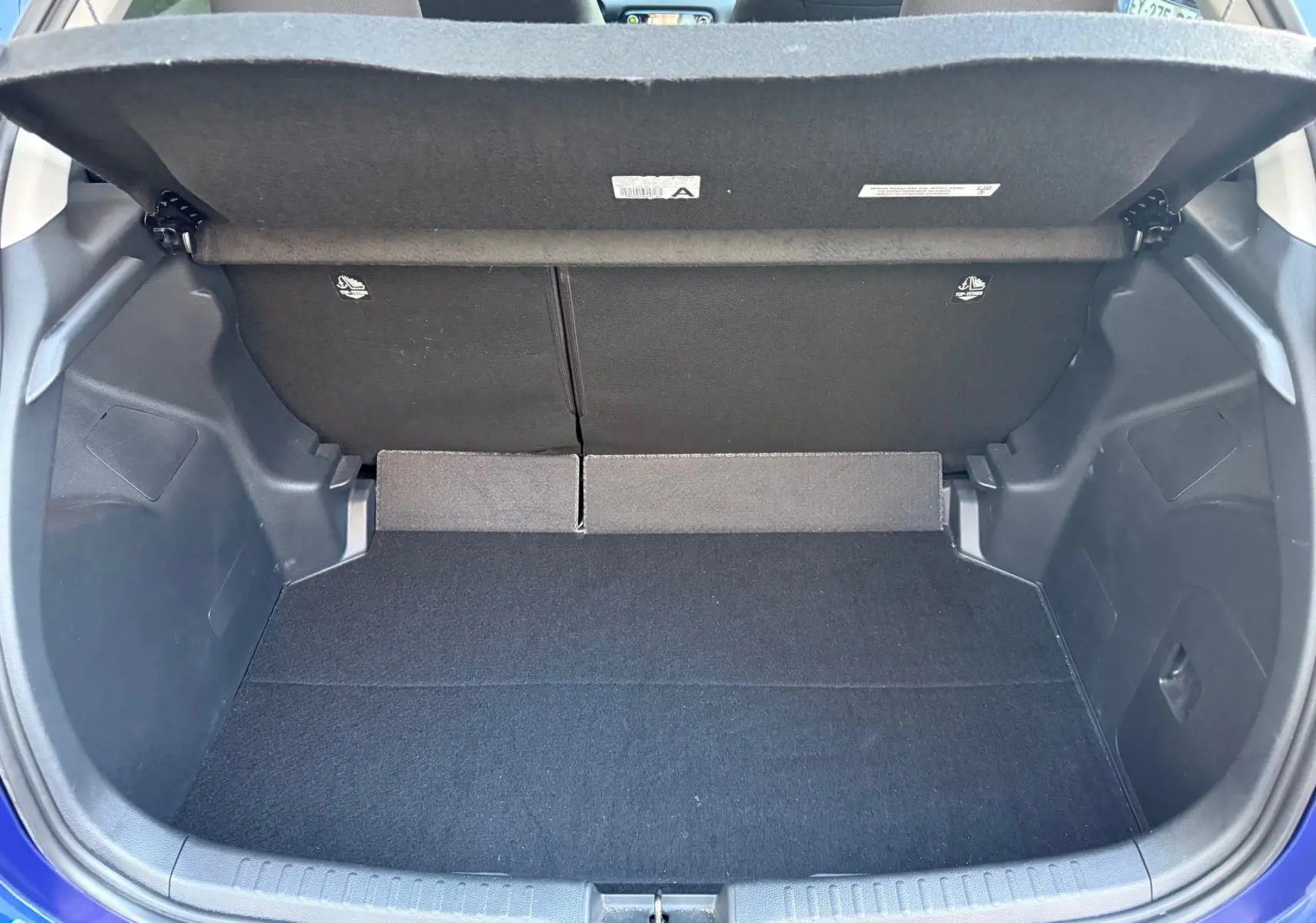 Coffre ouvert vu de l'arrière d'une Toyota Yaris Hybride Design 116h bleu métal, espace de rangement vide et propre.