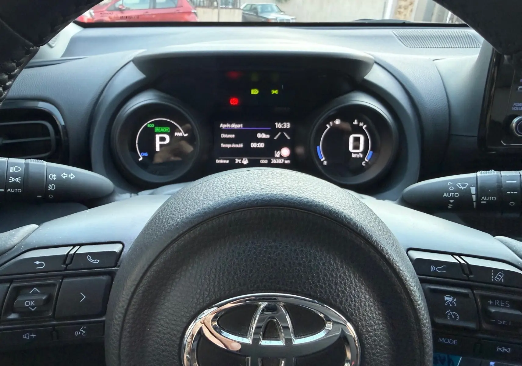Vue intérieure centrée sur le volant Toyota et le tableau de bord numérique de la Yaris Hybride 2021.