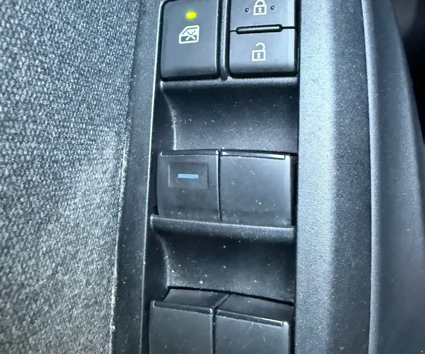 Gros plan sur les commandes de verrouillage et lève-vitres côté conducteur d'une Toyota Yaris Hybride bleu métal 2021.