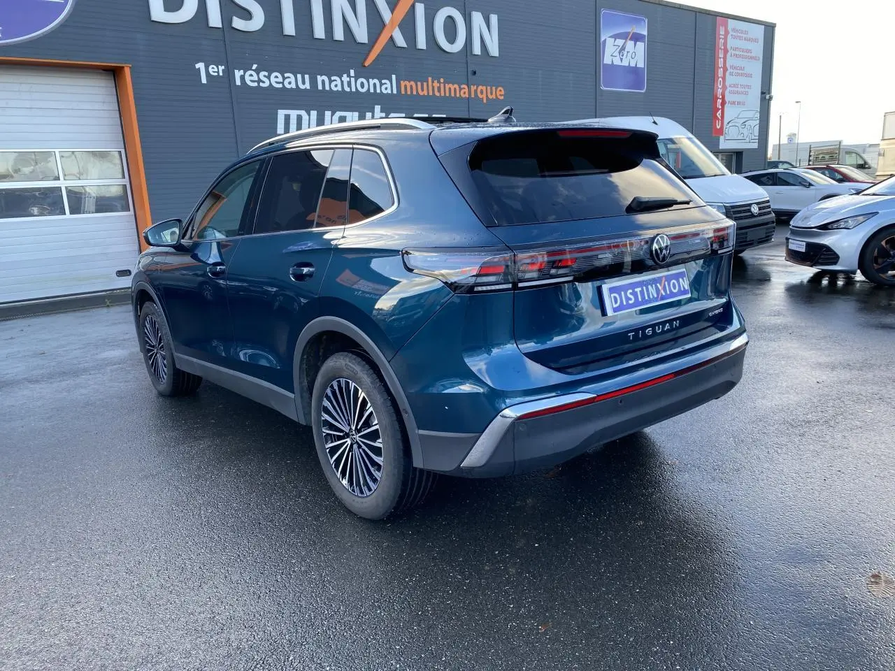 Vue 3/4 arrière droite du Volkswagen Tiguan 1.5 eHybrid bleu nuit métallisé avec jantes stylisées et vitres surteintées.