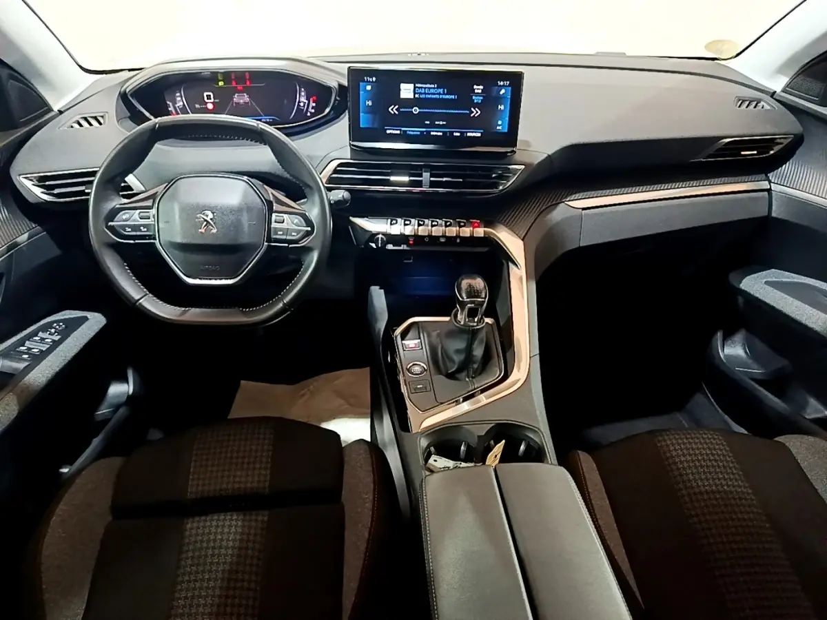 Vue intérieure avant du Peugeot 3008 2022 noir, tableau de bord numérique, écran tactile central et volant cuir multifonctions.