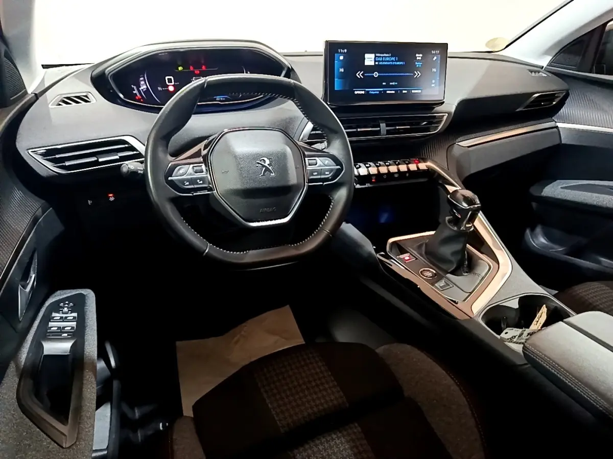 Vue intérieure du poste de conduite du Peugeot 3008 noir, avec volant cuir, écran tactile central et levier de vitesse manuel.