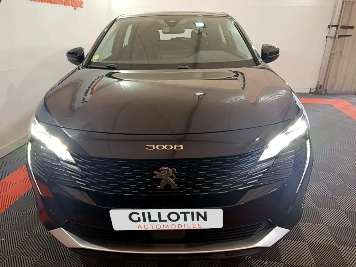 Vue avant du Peugeot 3008 noir 2022 avec phares allumés et calandre distinctive en intérieur showroom.
