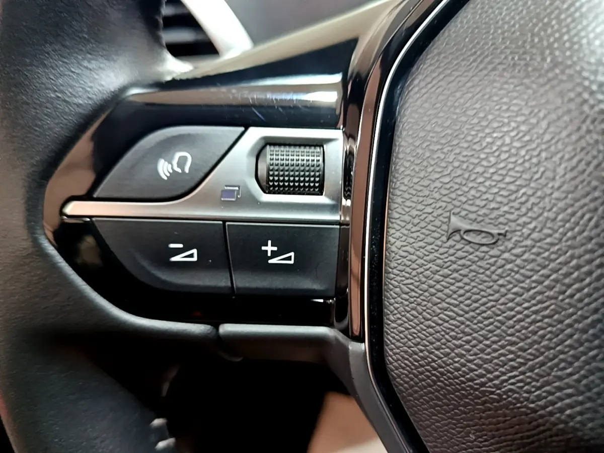 Gros plan sur les commandes gauche du volant noir du Peugeot 3008 2022, avec boutons de volume et commande vocale.