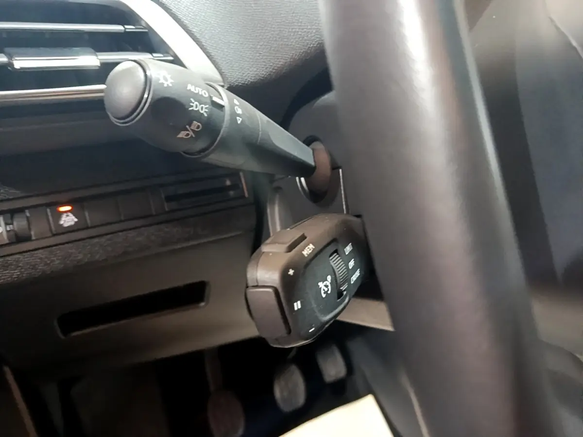 Gros plan sur la commande de régulateur de vitesse et le commodo d’éclairage dans l’habitacle noir du Peugeot 3008 2022.